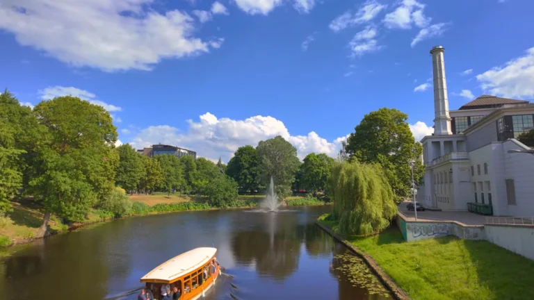 Canal boat passing through parkland in central Riga